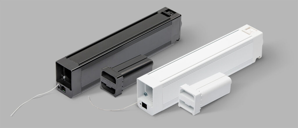 Czarny i biały mechanizm otwierania zasłon z widocznymi przewodami na szarym tle.